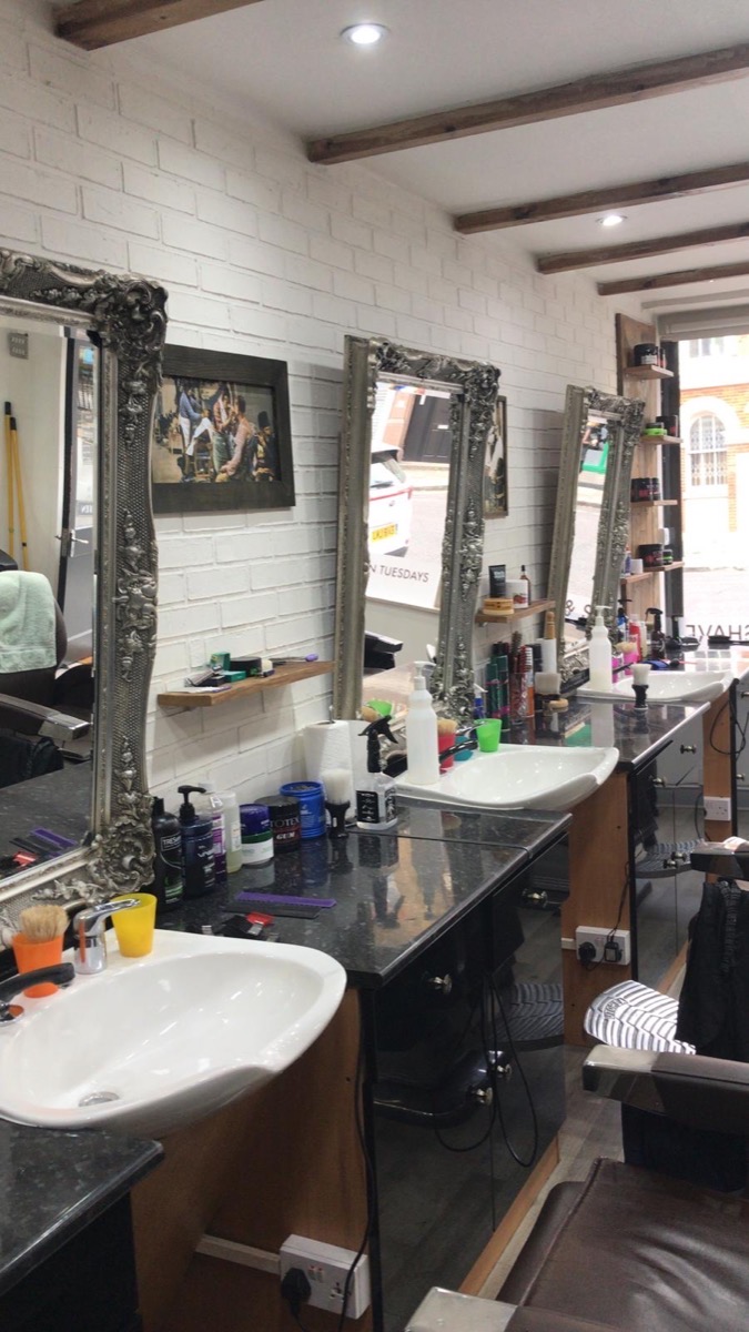 The mirror stations at Cutt Throat: ornate silver mirrors on white brick above black granite counters