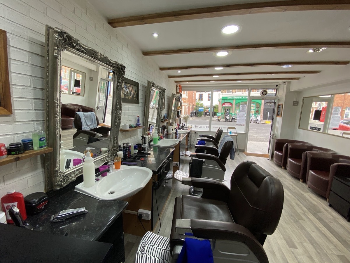 The full room at Cutt Throat barbershop, looking toward the Hoxton Street window past the row of barber chairs and mirrors